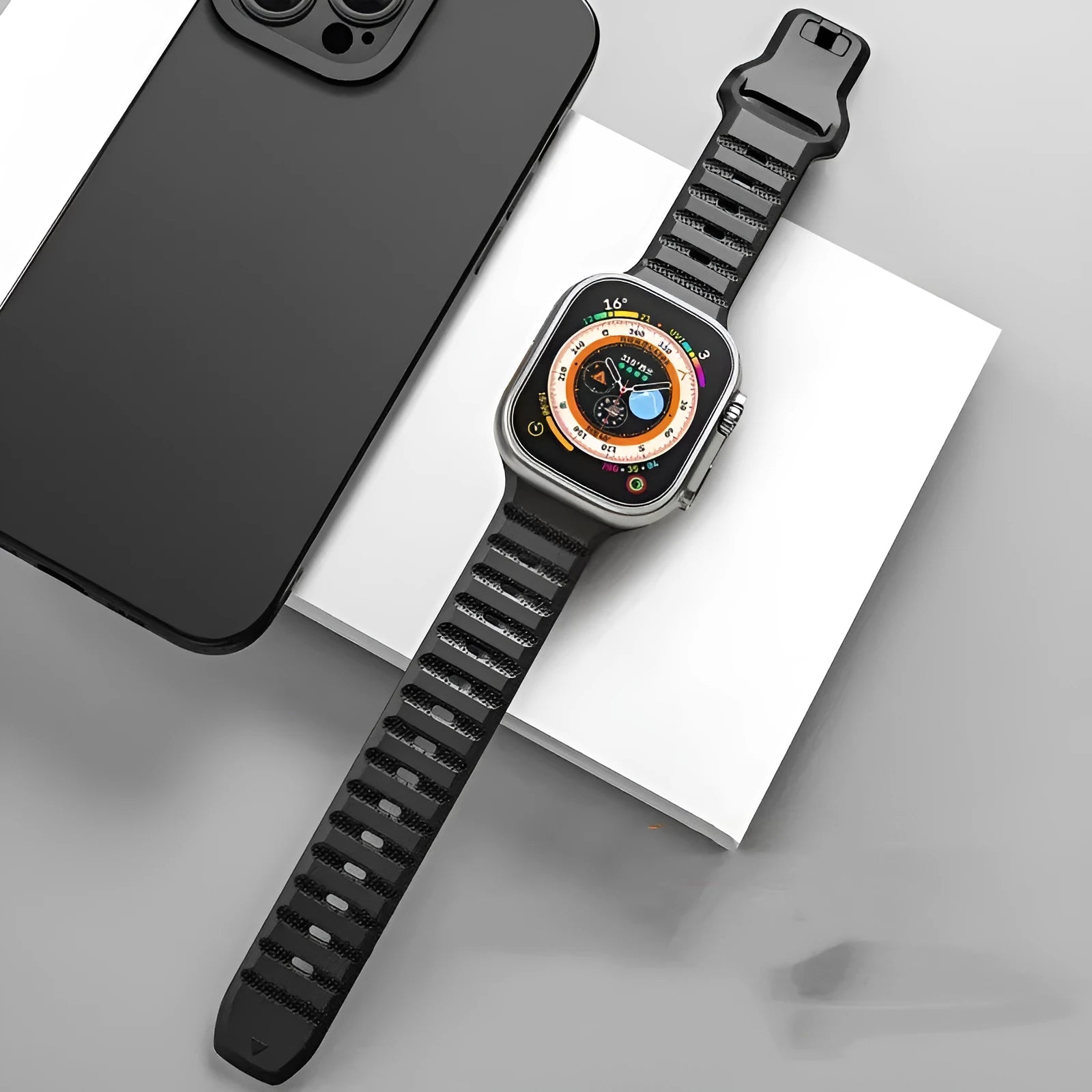 Black fluoro rubber Apple Watch band with silver T-buckle on a wrist, showing connection to Apple Watch case.