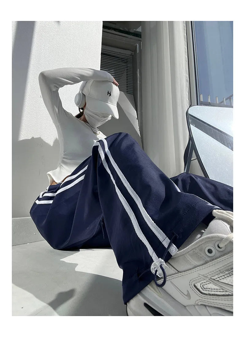 Women's navy blue straight-leg trousers with a white contrast ribbon detail sewn along the side seams.