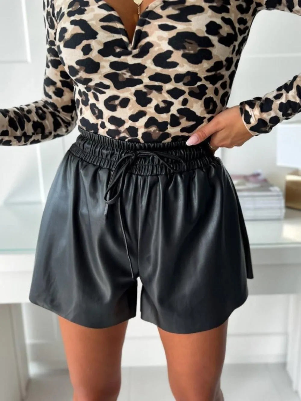 Black women's wide-leg shorts with lace-up drawstring detail on PU leather and straight-leg silhouette.