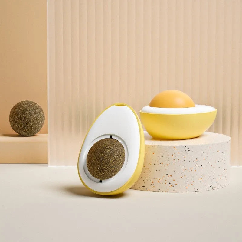 Catnip ball toy with adhesive backing attached to wall, showing cat head shape design