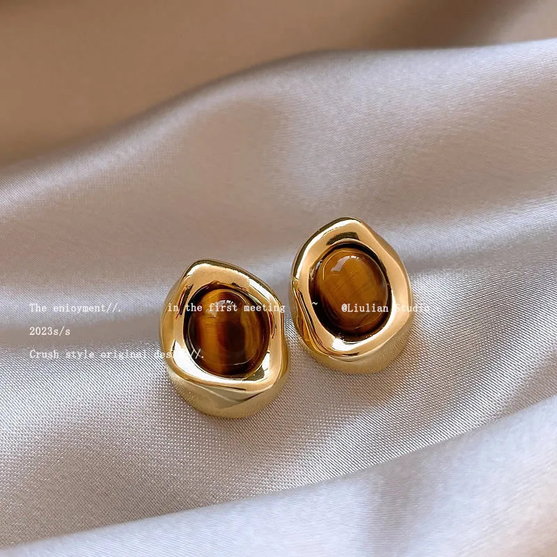 Set of three pairs of geometric holiday earrings: round studs, irregular amber studs, and tassel drop earrings.