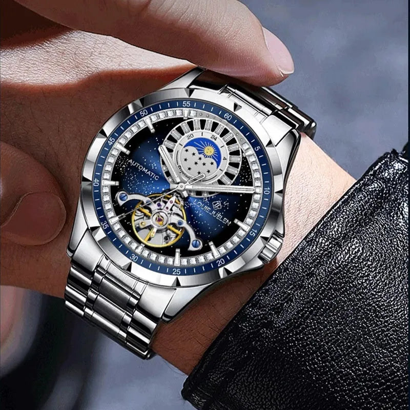 Men's silver automatic watch with blue dial on a stainless steel bracelet, showing transparent case back.