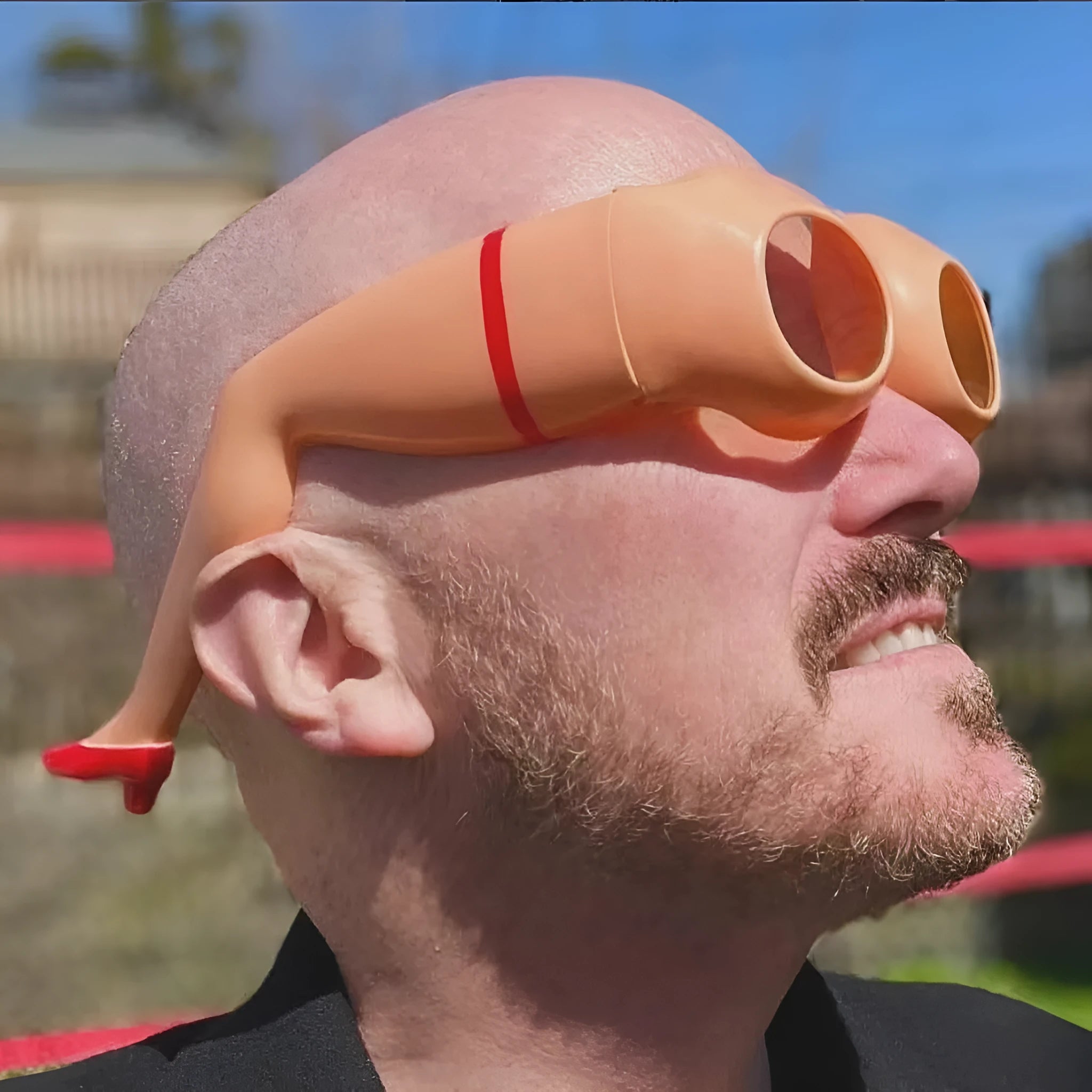Orange plastic novelty sunglasses with oversized leg hip design on a white background.