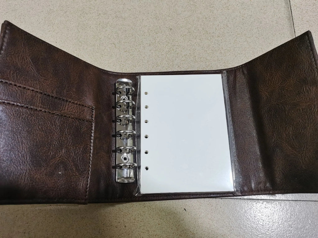 Brown retro-style A7 notebook with a PU leather-look cover and metal buckle closure, showing loose-leaf binding.