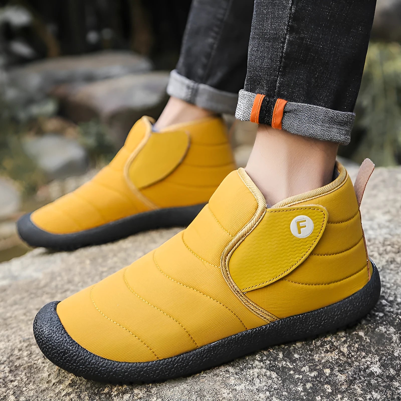 Men's thick black waterproof snow boots with a rubber sole on a hard surface.