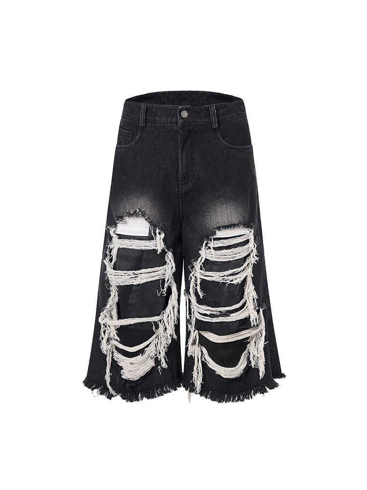Black wide-leg cropped jeans with a ripped patch detail on the leg, shown on a model.