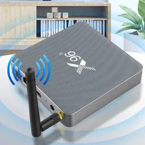 Android smart TV set-top box with voice remote control on a wooden table next to a television.