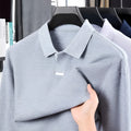 Man modelling a grey loose-fit cotton polo shirt with a lapel collar and asymmetric design.