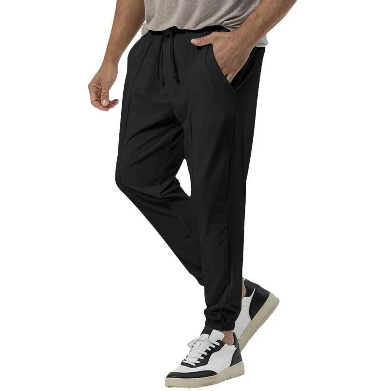 Man wearing grey loose tapered track sweatpants with a micro-elastic cotton blend fabric.