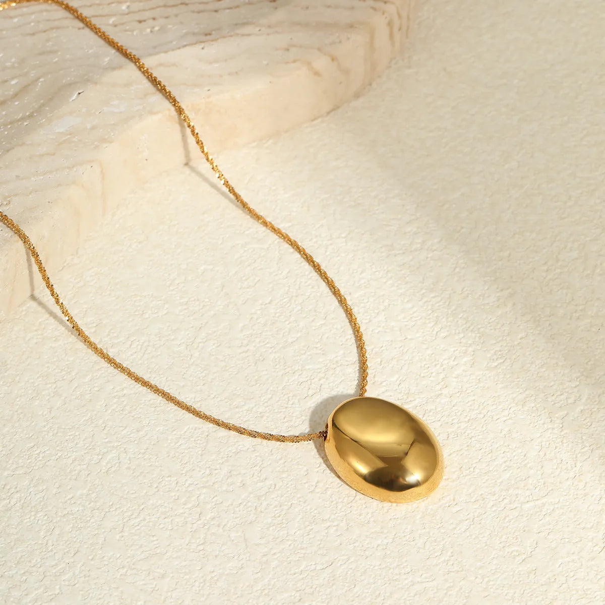 Gold geometric pendant necklace with adjustable chain on plain background
