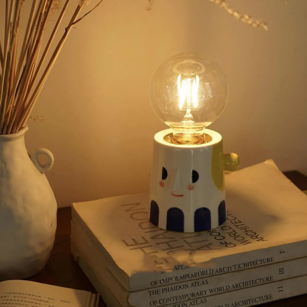 Handmade white ceramic table lamp with a spherical ball-shaped shade on a wooden surface.