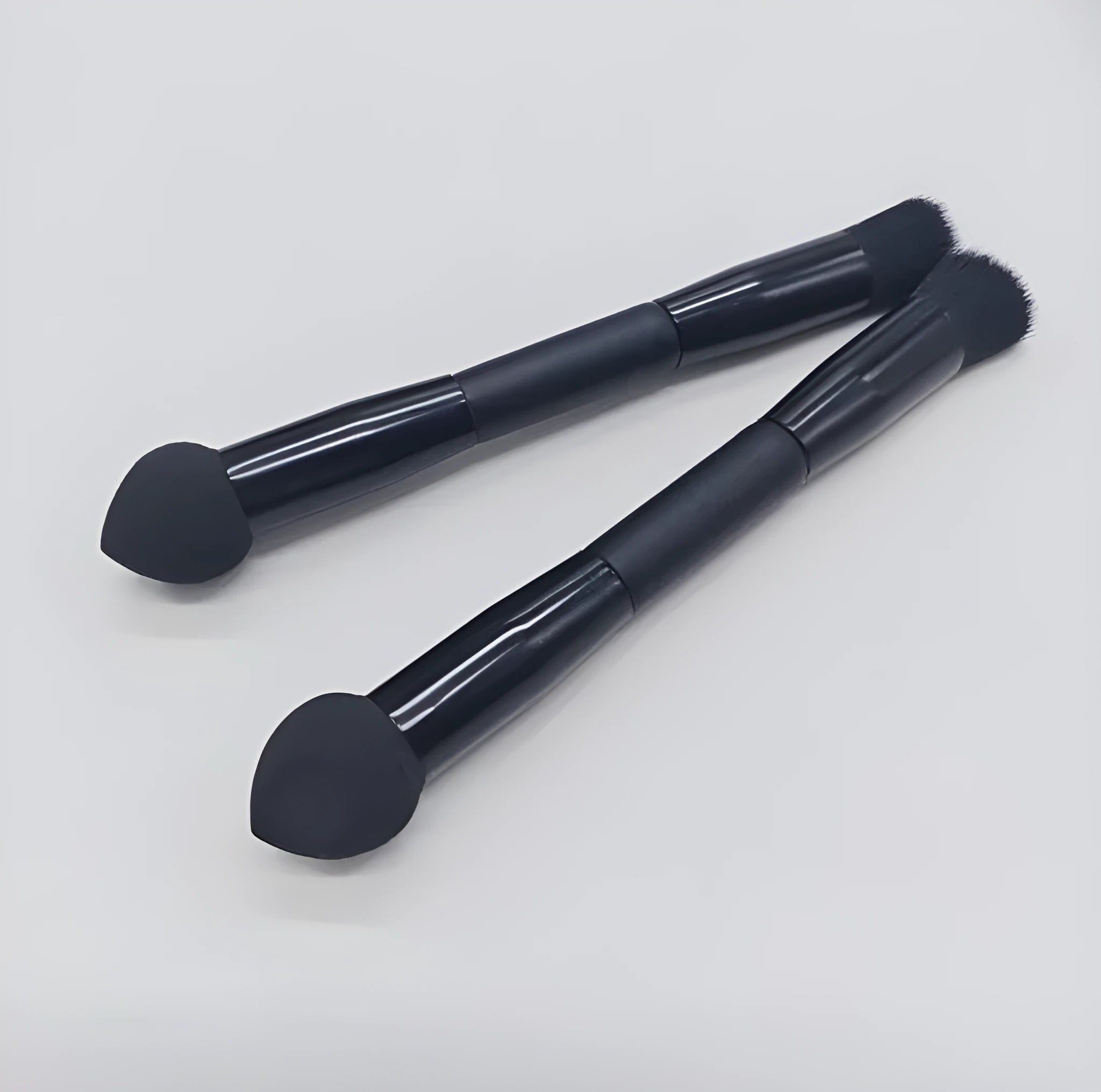 Double-headed concealer brush with black wooden handle, artificial fibre bristles, and angled sponge tip.