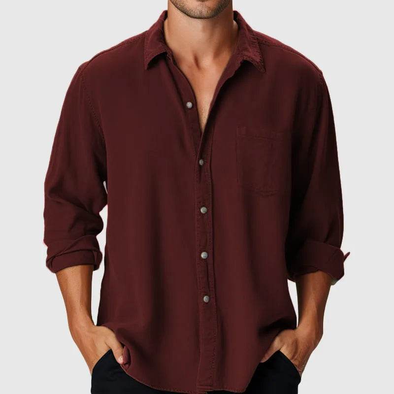 Man wearing a loose fit long sleeve shirt with a stand collar on a beach.
