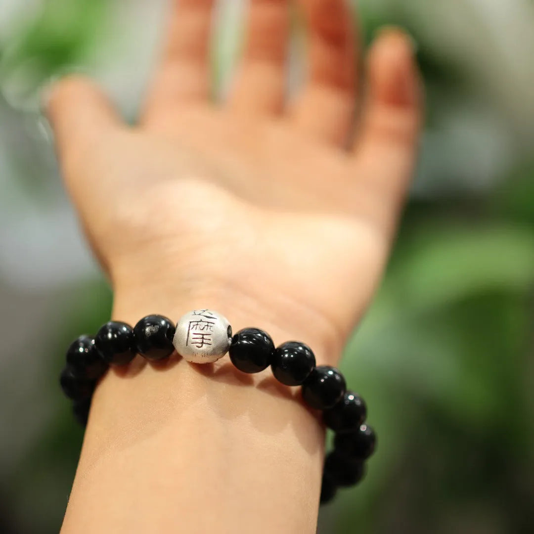Close-up of a black agate bead bracelet with a sterling silver adjustable clasp on a wrist.