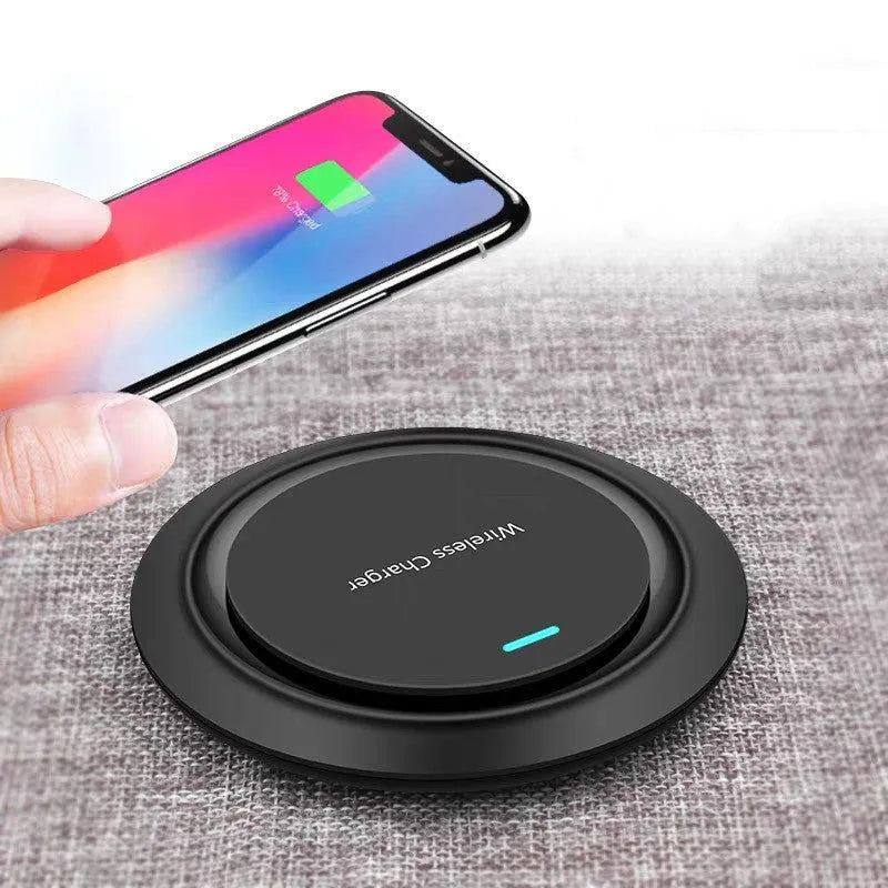A round, slim 7mm thick 10W desktop wireless phone charger in black or white on a desk.