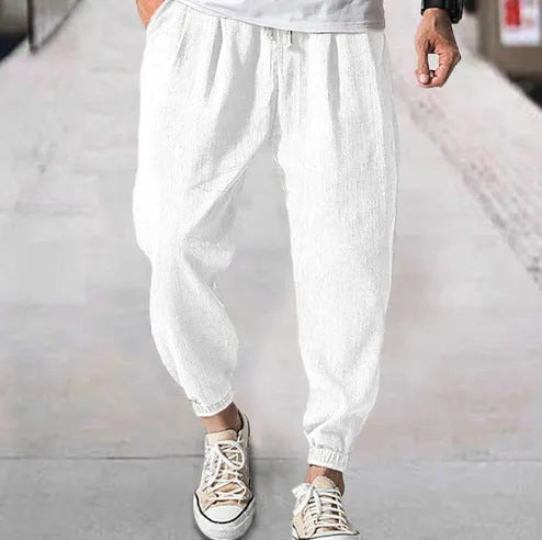 Men's loose-fit light green cotton casual trousers with a banded ankle cuff on a plain background.