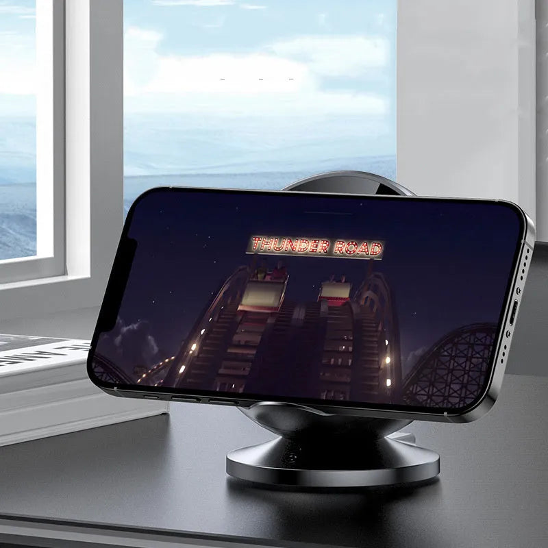 Black multifunctional wireless charging phone holder with built-in Bluetooth speaker on a desk.