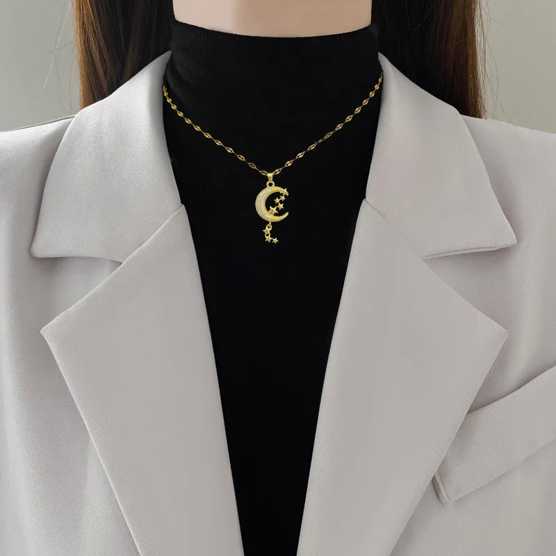 Geometric moon pendant necklace with crystals and tassel detail on an adjustable stainless steel chain.