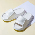 A pair of thick-soled EVA flip-flop slippers on a bathroom floor, showcasing non-slip tread and available colour options.