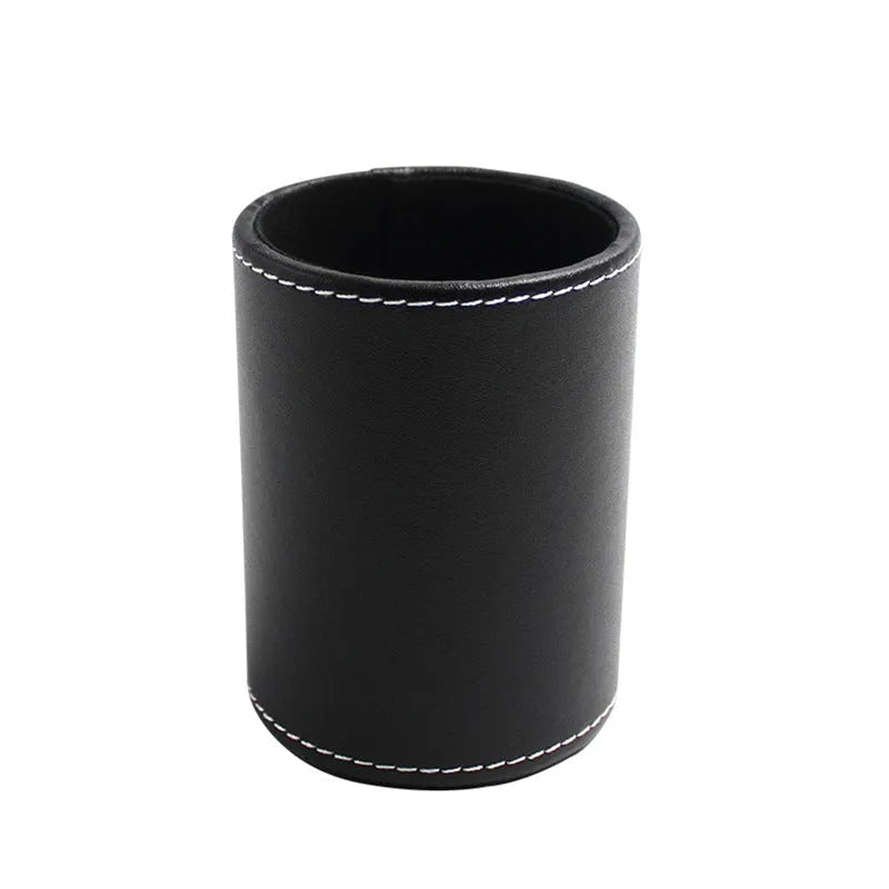 A small, round black leather pen holder standing on a wooden desk.
