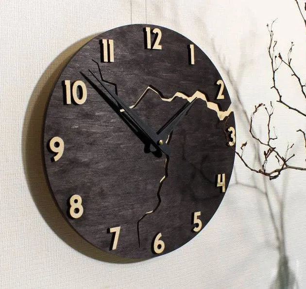 Modern simple wooden wall clock with a crack design dial on a light wood background.