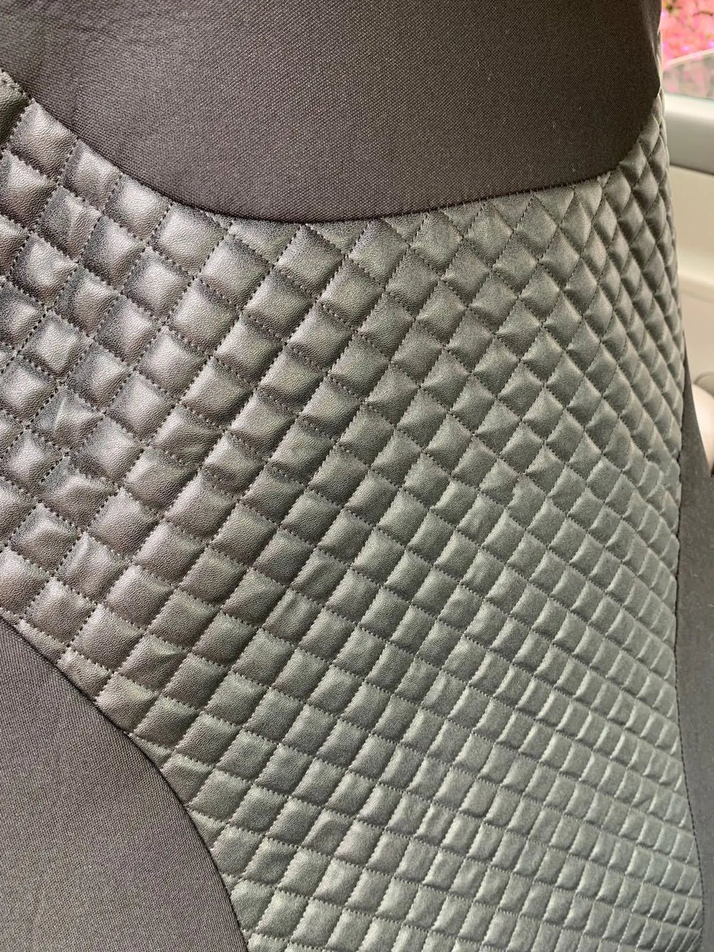 Black quilted automotive seat cover made of PU and polyester fabric on a car seat.