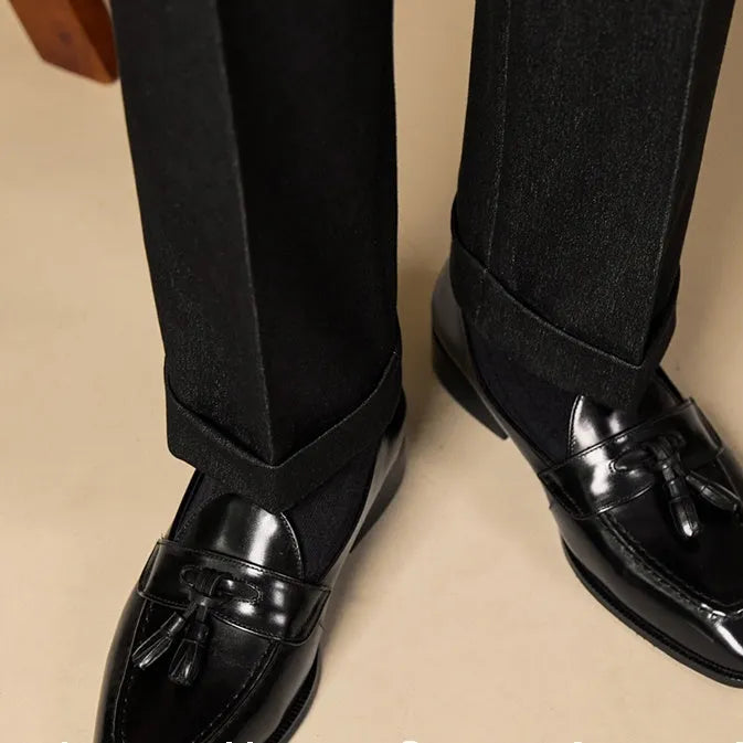 Men's black and brown polished leather tassel loafers for business casual wear, shown from the side.