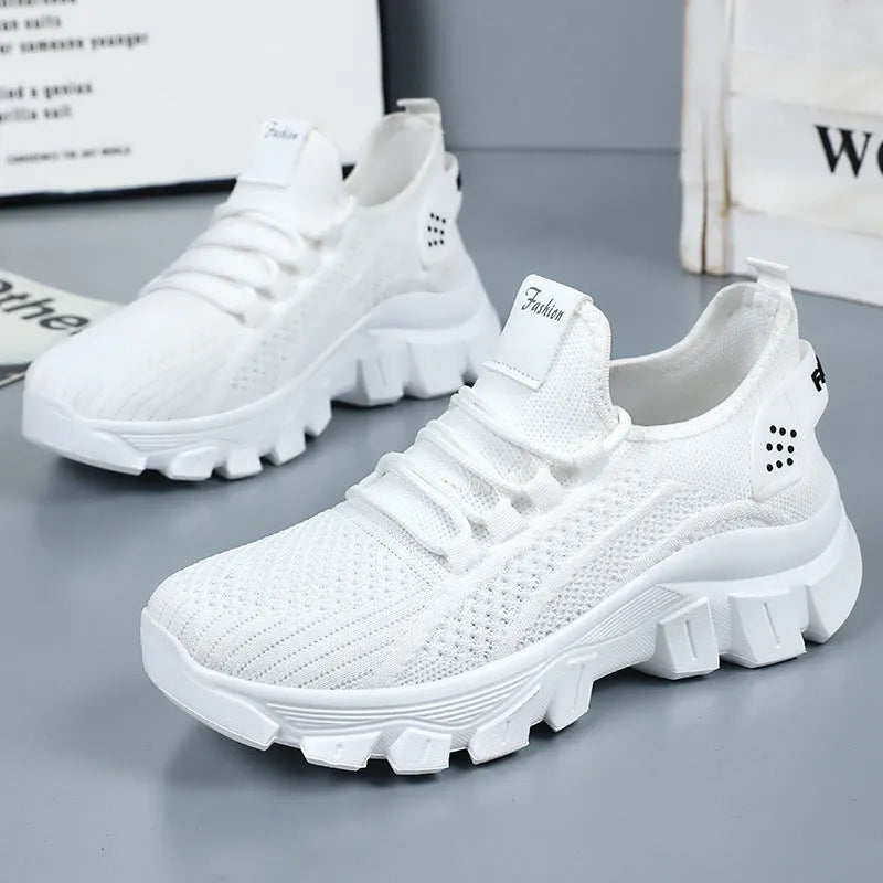 Women's white Flyknit sneakers with thick PVC sole and lace-up front on a neutral background.