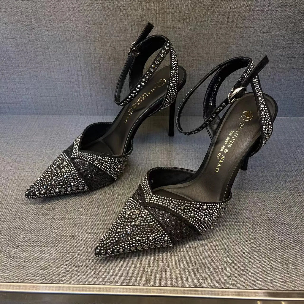 Women's silver and black hollow stiletto high heels with pointed toe and red sole on a plain background.