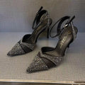 Women's silver and black hollow stiletto high heels with pointed toe and red sole on a plain background.