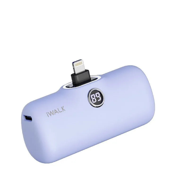 Compact white lipstick-shaped power bank with digital battery percentage display on a wooden table.