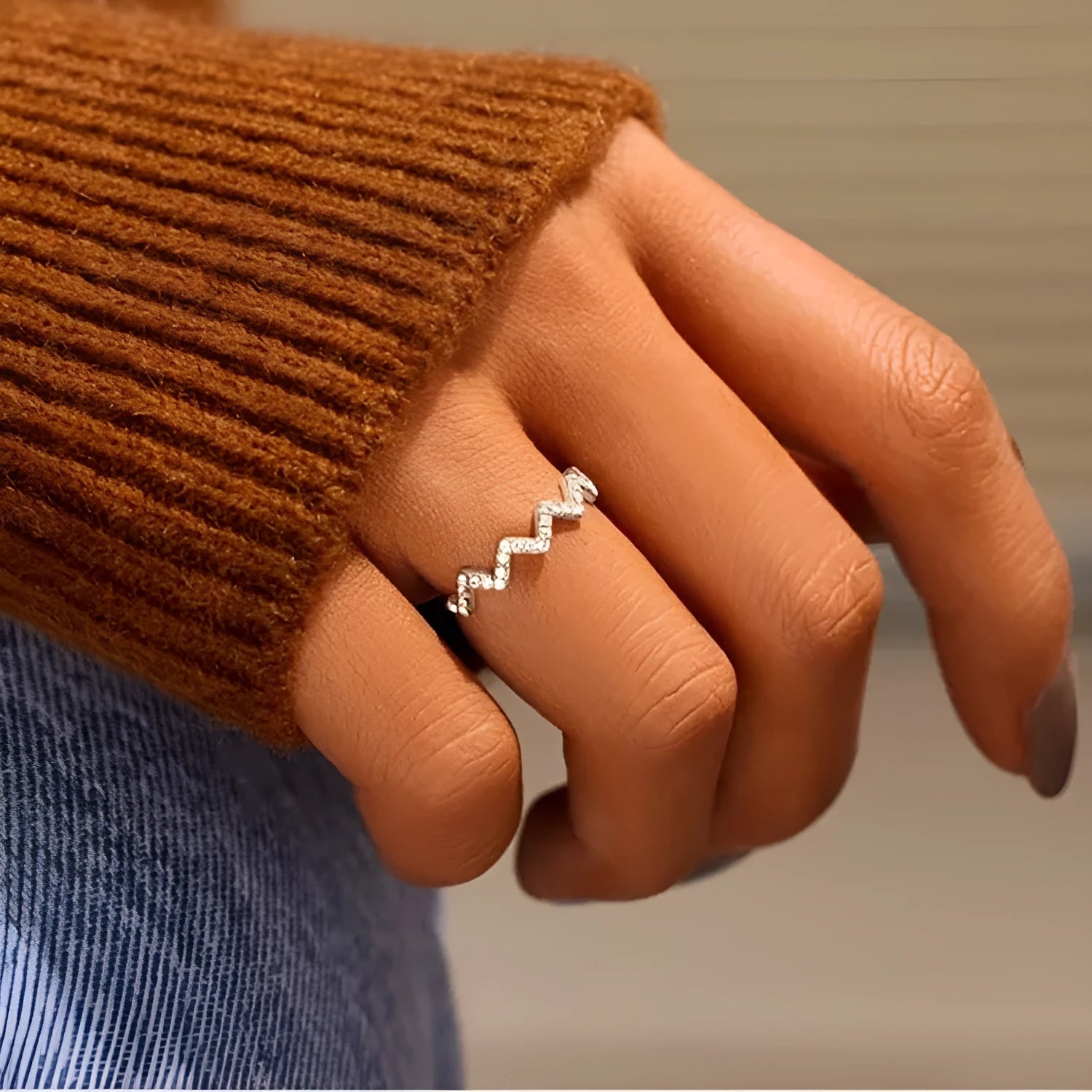 Sterling silver wave pattern adjustable ring with gem inlay, gold colour, against neutral background