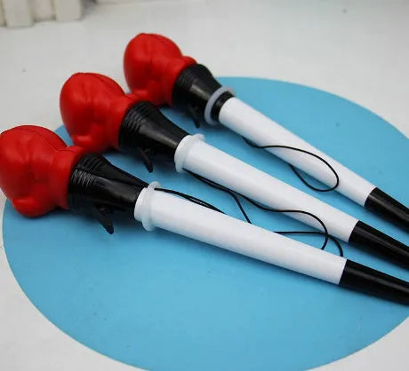 Boxing pressure pen ejection press stationery toy with four black pens on a desk.