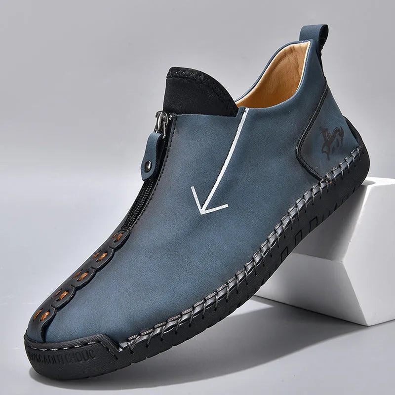 Men's black leather ankle boots with a front zip and hand-stitched detailing on a rubber sole.
