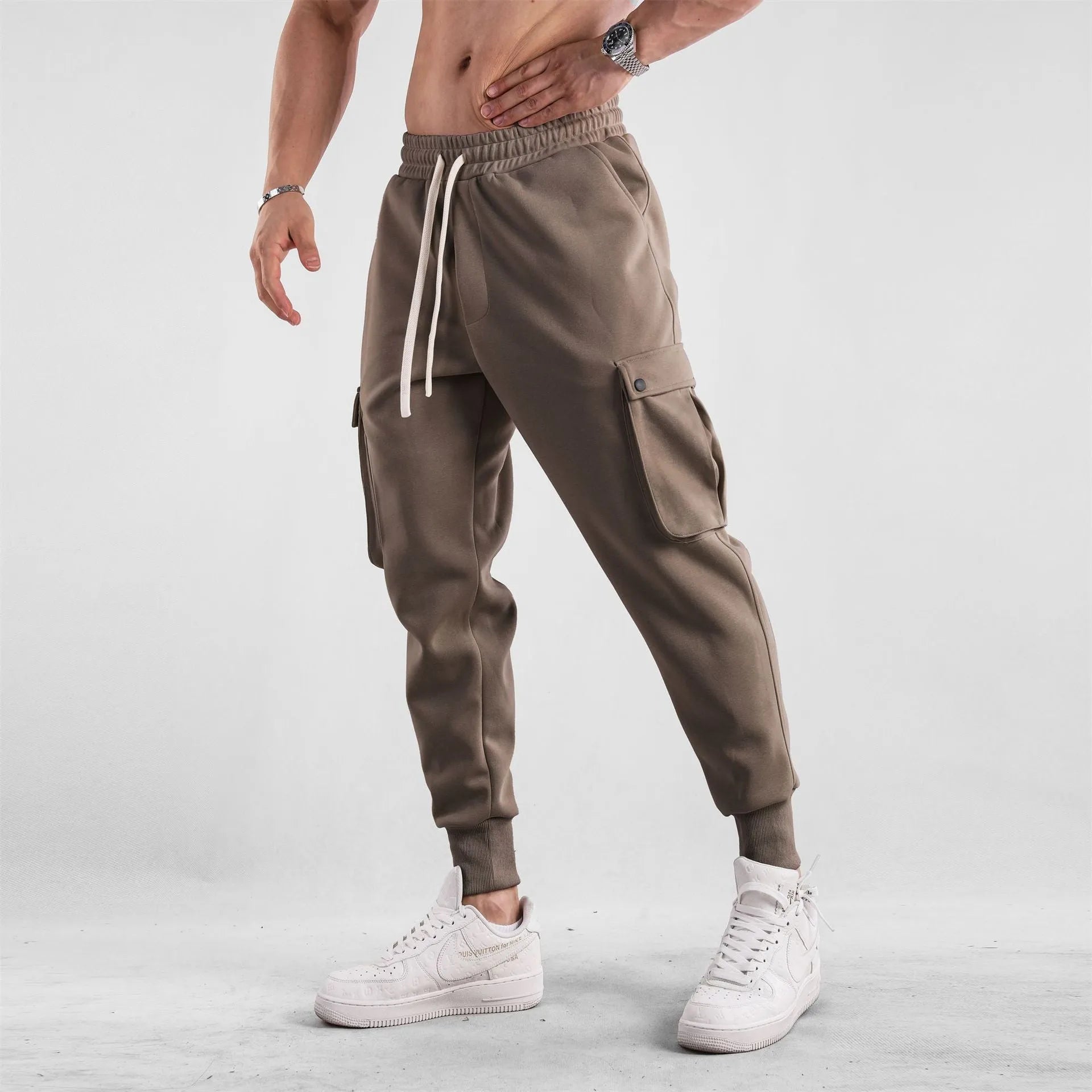 Men's loose-fit apricot coloured cotton sports trousers with an ankle tie and side pockets on a neutral background.