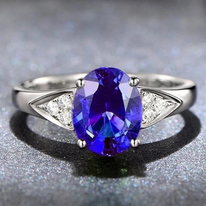 Close-up of a women's court-style silver-toned ring with an inlaid red natural zircon stone cut in a heart shape.