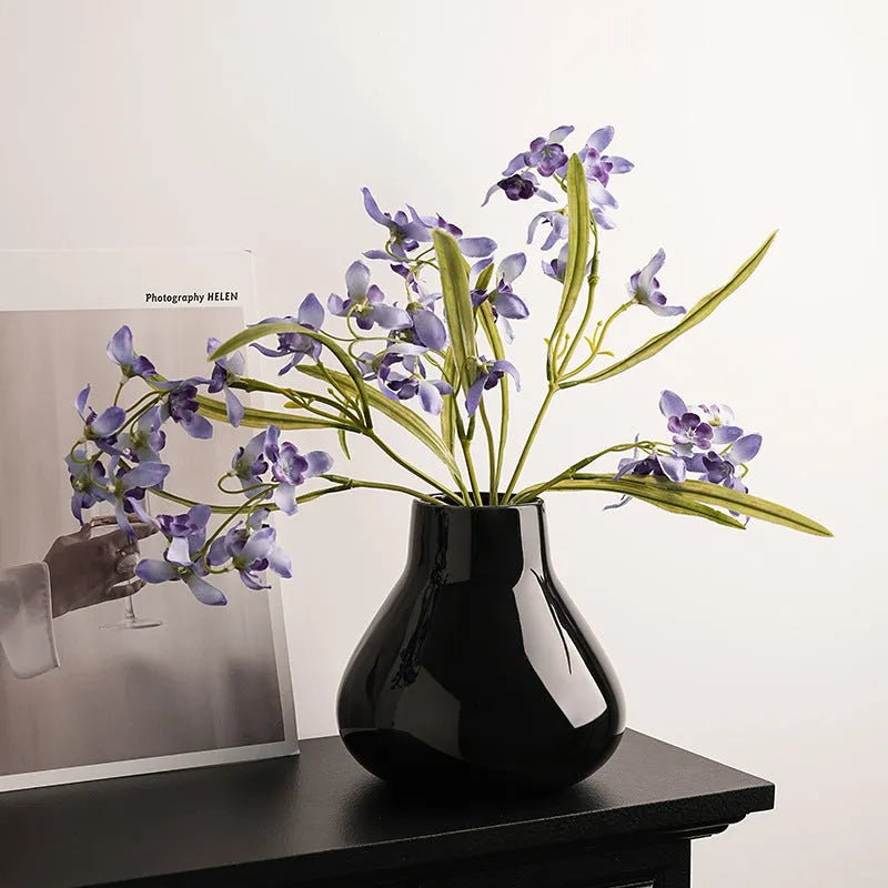 Modern ceramic vase with two white artificial orchid stems in minimalist home setting