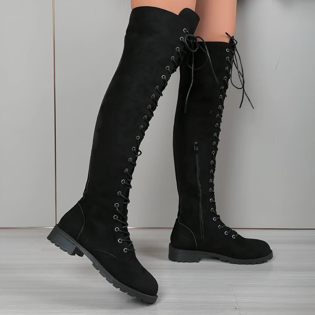 Black lace-up over-the-knee boots with a round toe and flat sole on a neutral background.