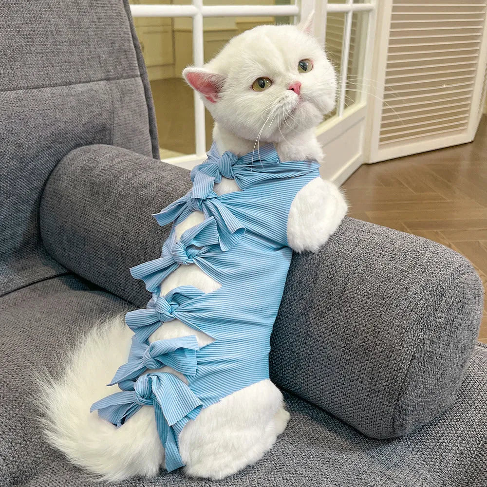 Pink lace-up cat recovery bodysuit on a table, showing back ties and full-body design for post-surgery care.