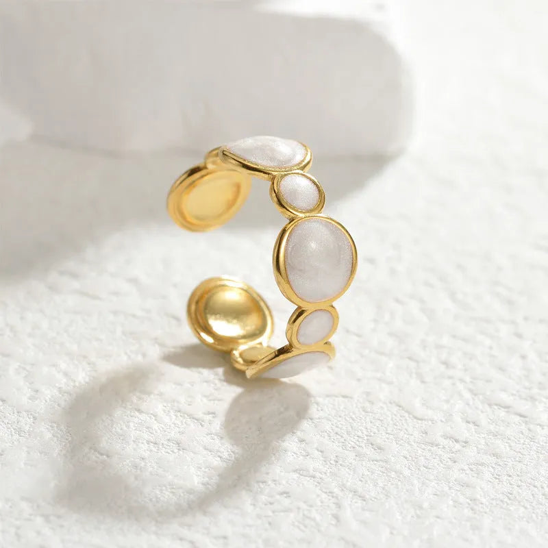 A stainless steel ring with a geometric design and adjustable opening on a plain background