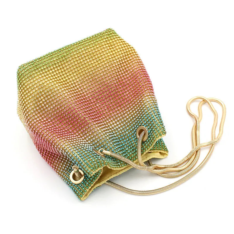 Soft rainbow rhinestone bucket handbag with adjustable long strap on a neutral background.