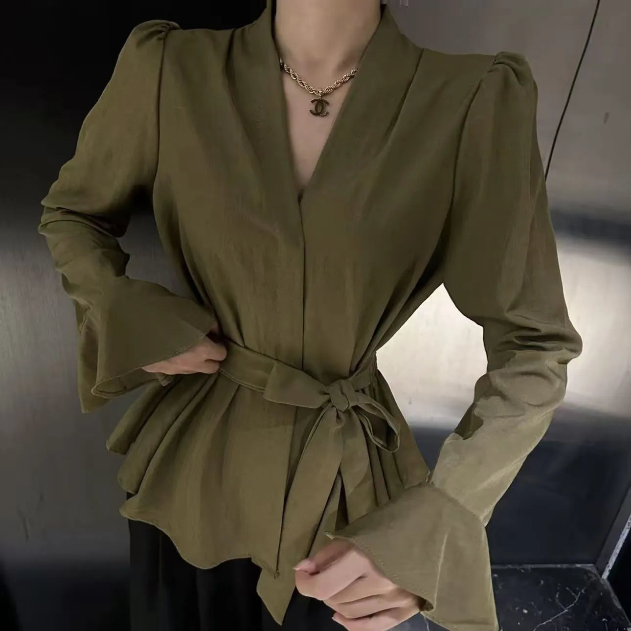 A woman wearing a black French-style shirt with an irregular collar and long bell sleeves.