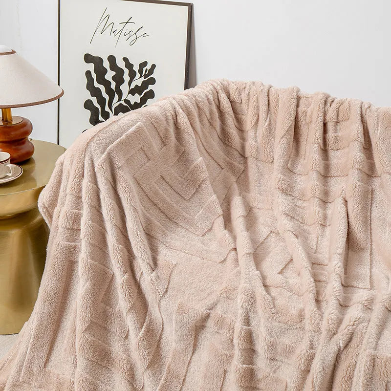 Thick square coral fleece flannel blanket in a solid colour, folded on a sofa.