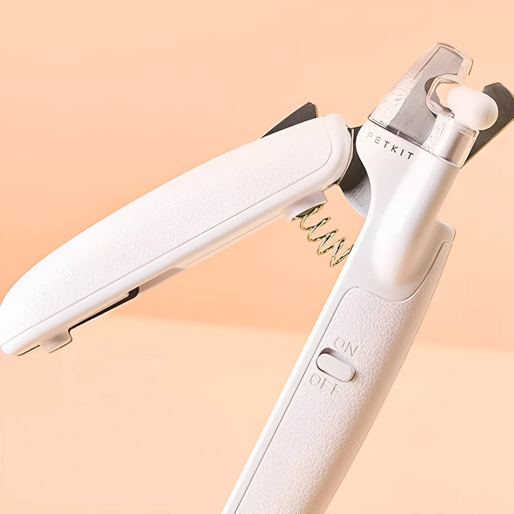 White pet nail clippers with LED light and transparent anti-splash guard next to a nail file on a table
