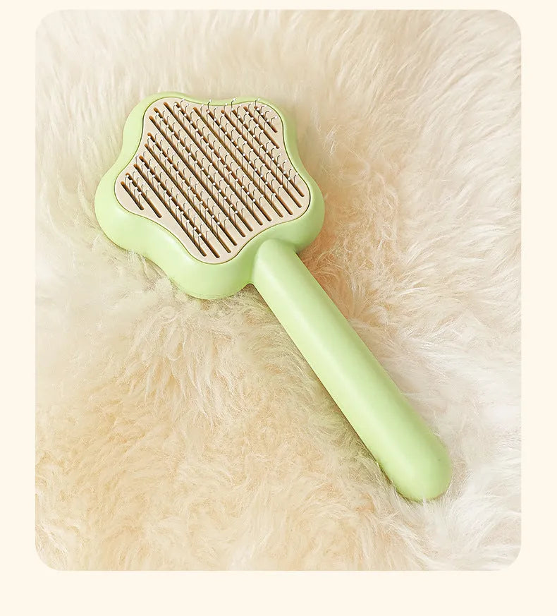 Green self-cleaning pet comb with stainless steel needles on a white background.