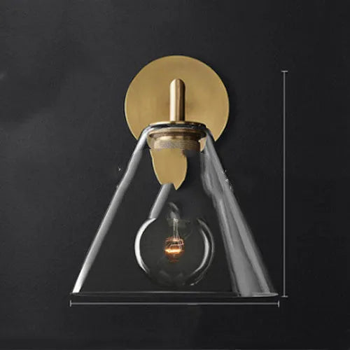 Gold bronze or black wall lamp with triangular transparent glass shade and wrought iron frame for bedside or hallway use