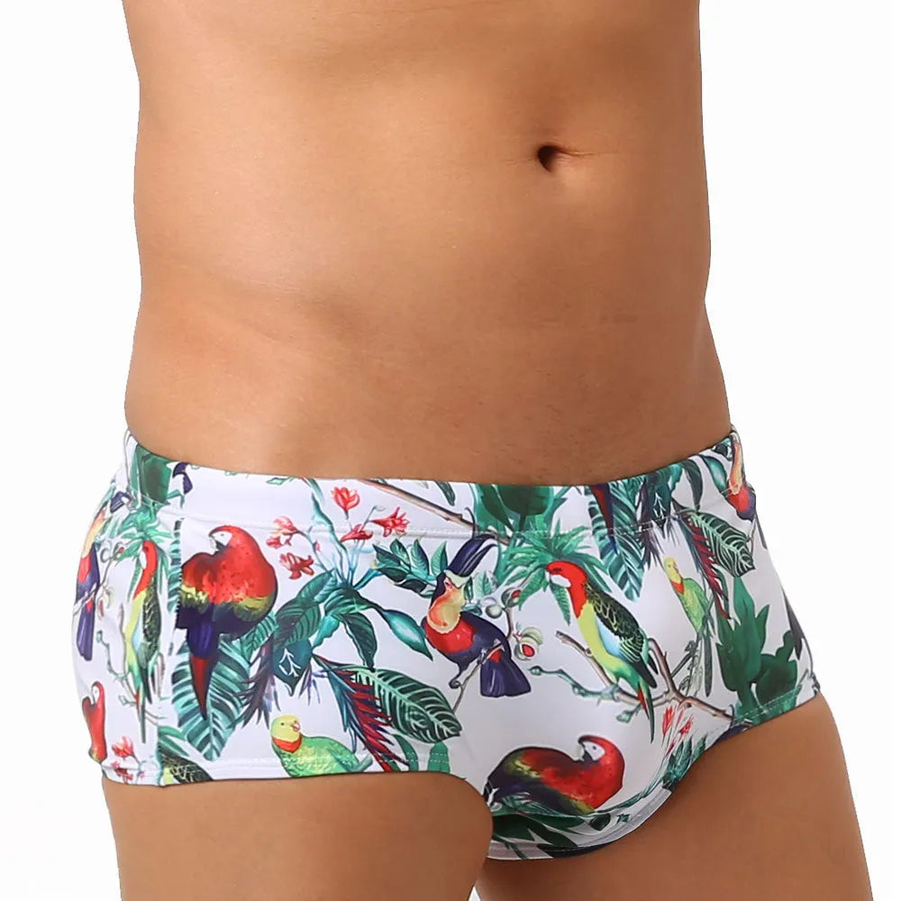Men's blue swimming trunks with a detailed floral and bird print pattern, small boxer style