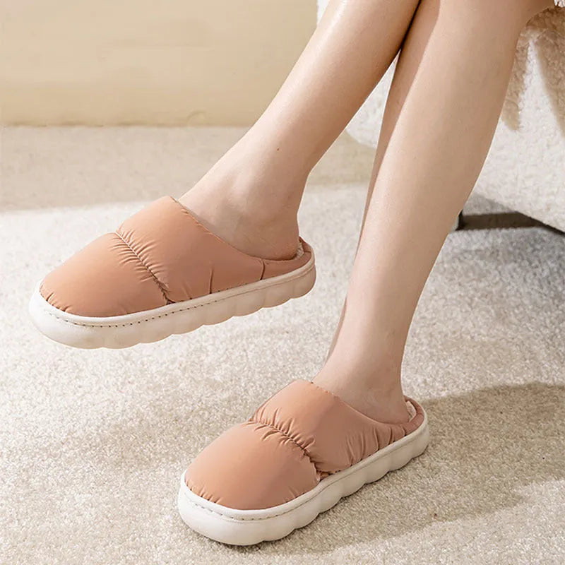 Blue down cotton winter slippers with a thick rubber sole and plush lining, shown on a wooden floor.