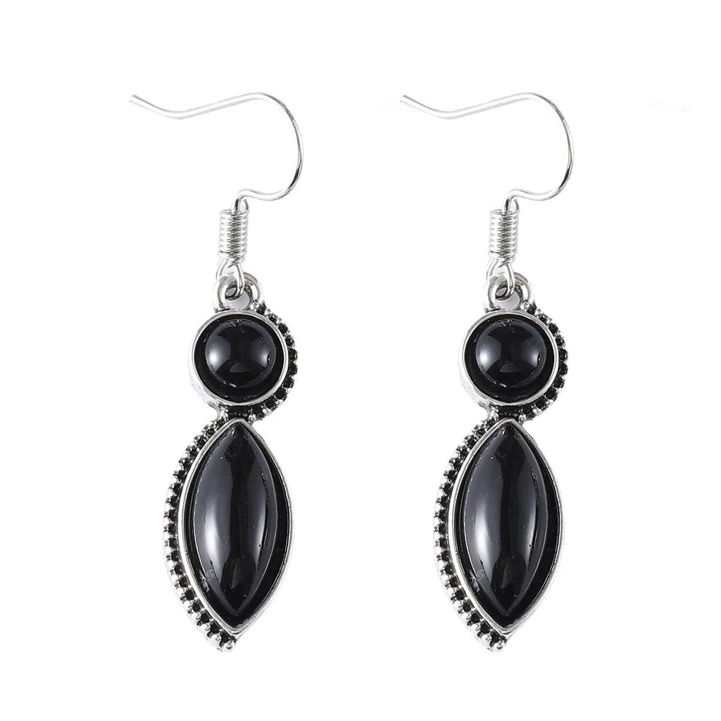 Close-up of vintage black and purple geometric drop earrings with a circular pendant on a long chain.