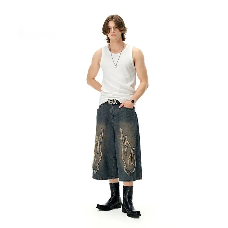 Men's black denim shorts with flame embroidery patch detail on straight leg cropped design